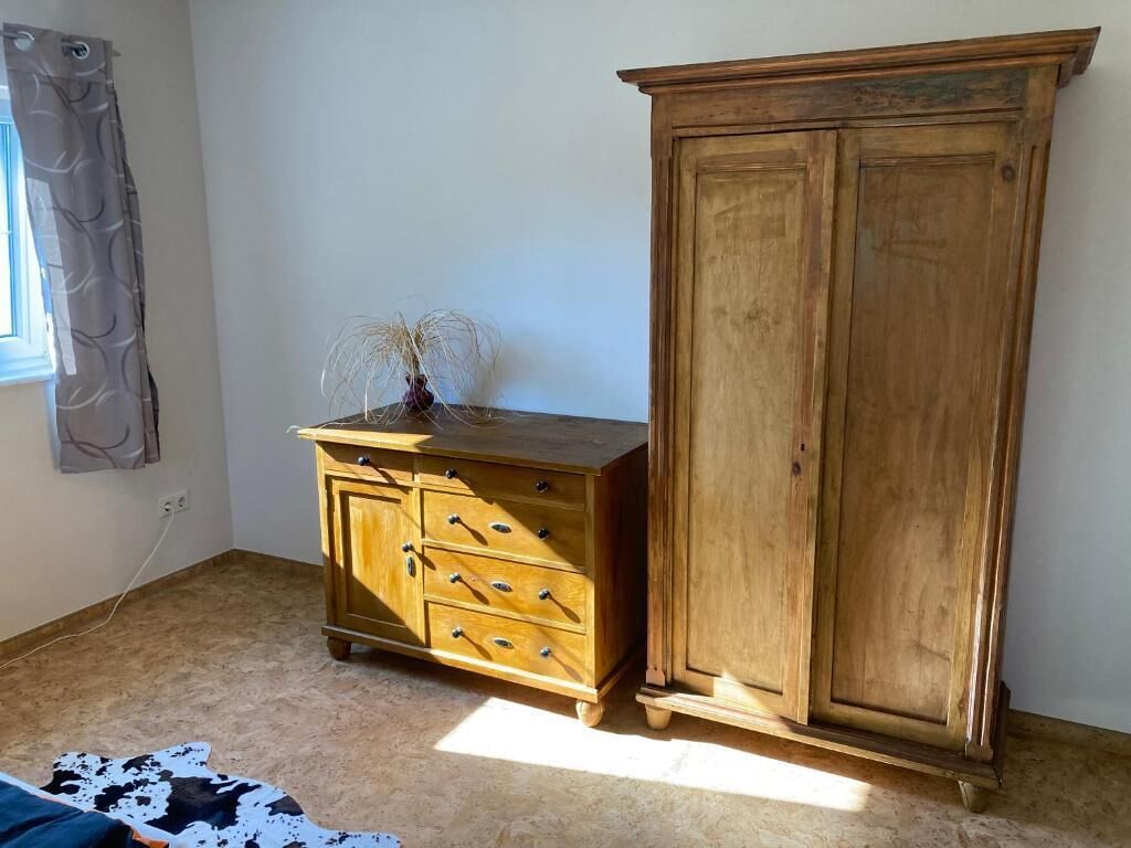 A room with a wooden cabinet with drawers and a tall cabinet with two doors.