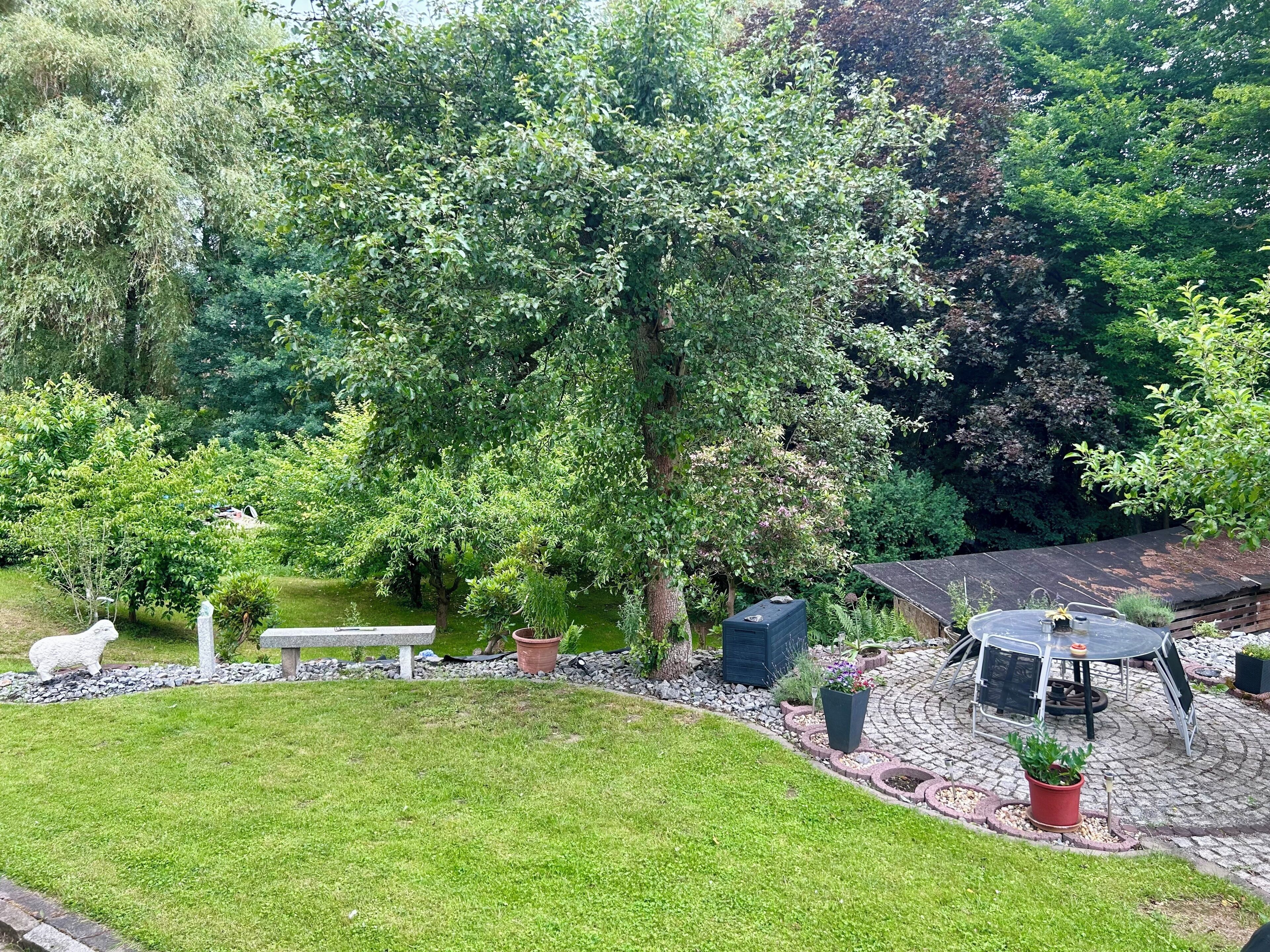 A garden with a patio area, a white sculpture, and a pond.