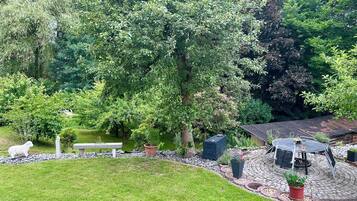 A garden with a patio area, a white sculpture, and a pond.