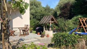 Patioterassi ulkokalusteineen, pergola aurinkopaneelilla sekä puinen keinuteline.