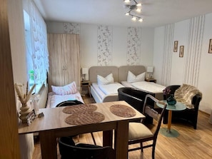 Quarto compacto com cama, sofá, mesa de jantar e uma cadeira.
