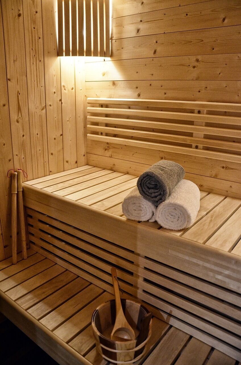 A wooden sauna with benches, towels, and wooden utensils.