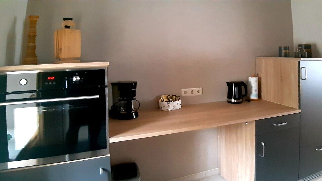 Une cuisine équipée d’un four encastré, d’une machine à café et d’un placard.