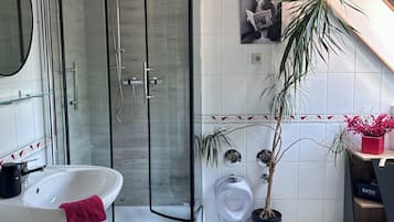 Un bagno moderno con box doccia in vetro, un lavandino bianco, un water e una pianta in vaso.