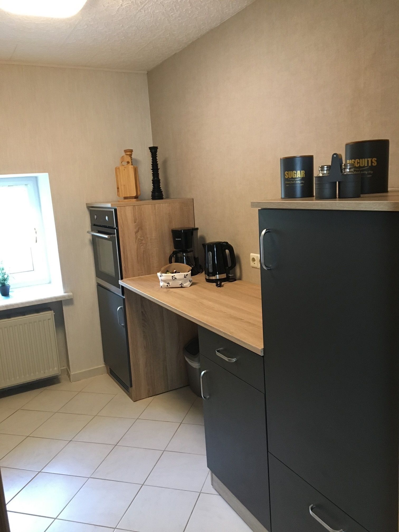 A kitchen with a stove, oven, coffee maker, and cabinets.