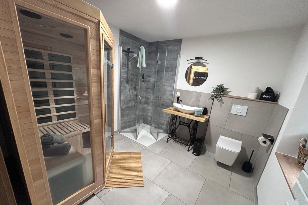 A modern bathroom with a wooden shower enclosure, a sink with a mirror above, and a toilet.