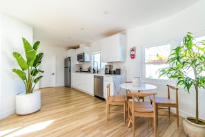 A modern kitchen with white cabinets, stainless steel appliances, and a dining area with a round table and wooden chairs. - Marvelous 5-bedroom house with pool (Palm Springs)
