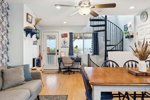 Ein modernes Wohnzimmer mit Sofa, Esstisch, Schreibtisch und einer Treppe.