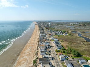 Luftaufnahme einer Küstenstadt mit Strand, Wohnhäusern und einem Wasserturm.