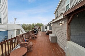 Eine Holzterrasse mit Gartenmöbeln, einem Grill und einem überdachten Bereich mit Tisch und Stühlen.