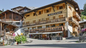 A wooden building with multiple balconies and a sign reading 'Chalet des Aravis.'