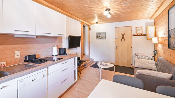 A modern kitchen with white cabinets, a black stove, and a Siemens dishwasher.