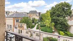 Een straatbeeld met gebouwen, een boom en een bord waarop 'SQUARE DES VICTIMES DE LA GESTAPO' staat.