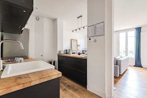 A modern kitchen with a sink, cabinets, and a wooden countertop. - Le Jeanne d’Arc – City center & sleeps 8 (Reims)
