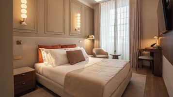 A hotel room with a large bed, bedside tables, a desk with a chair, a TV, and wall-mounted lighting.