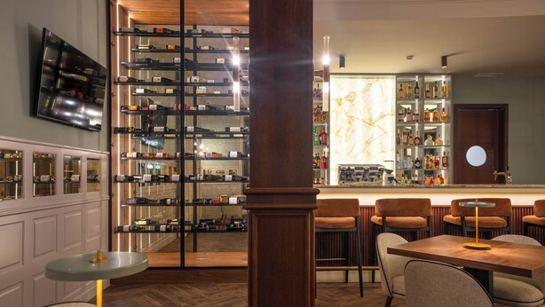 A bar area with a wine rack, seating, and a television. - The Book Hotel (Horta)