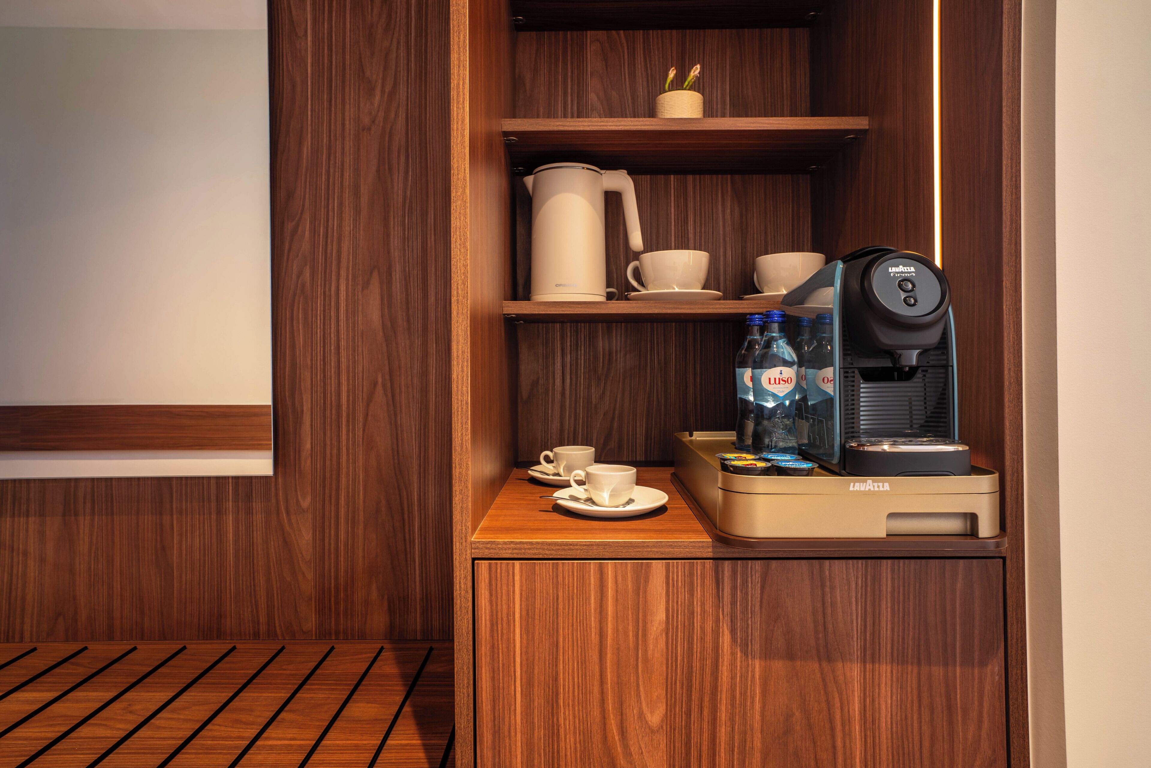 Un mueble de madera con cafetera, tazas y dispensador de agua.