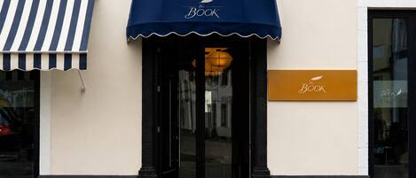 A storefront with a blue awning and a sign that reads 'the Book.'