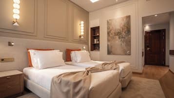 Habitación de hotel con dos camas, una mesita de noche, una lámpara de pared y un cuadro abstracto grande.
