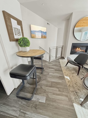 Una sala de estar moderna con chimenea, una mesa redonda, una silla negra y una pequeña planta en maceta.