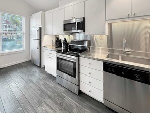 A modern kitchen with stainless steel appliances, white cabinetry, and a herringbone-patterned floor. - Lovebirds paradise by Main Street (Park City)