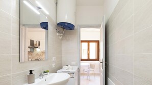 A bathroom with a sink, mirror, and towel dispenser. - Studio Aura by Propertize - centro Olbia (Olbia)