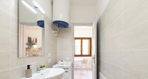 Ein Badezimmer mit Waschbecken, Spiegel und Handtuchspender.