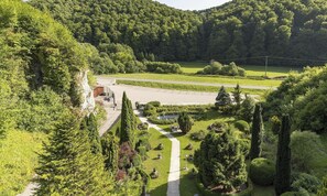 Ein angelegter Garten mit Wegen, einem kleinen Gebäude und einer Straße im Hintergrund.
