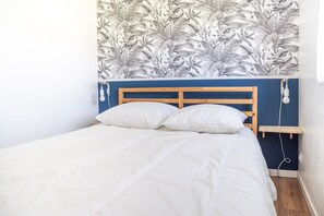 Ein Bett mit weißer Bettwäsche, einem Holz-Kopfteil und einer Wand mit einem Blattmuster.