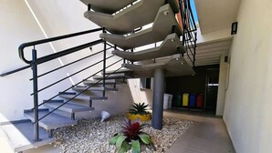 A modern outdoor staircase with metal railings, surrounded by pebbles and potted plants. - Fully furnished apartment near the beach and Beto Carrero World! (Penha  SC)