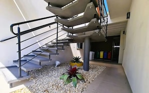 A modern outdoor staircase with metal railings, surrounded by pebbles and potted plants. - Fully furnished apartment near the beach and Beto Carrero World! (Penha  SC)