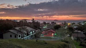 A residential area with houses, a body of water, and a distant island. - Fully furnished apartment near the beach and Beto Carrero World! (Penha  SC)