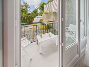 An open door to a balcony with a white table, blue railing, and white chairs. - 100 m from the sea – Apartment for 4 with terrace (Bénodet)