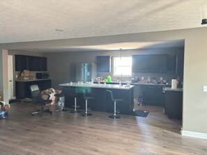 A spacious kitchen with dark cabinets, a large island with bar stools, and a window providing natural light.