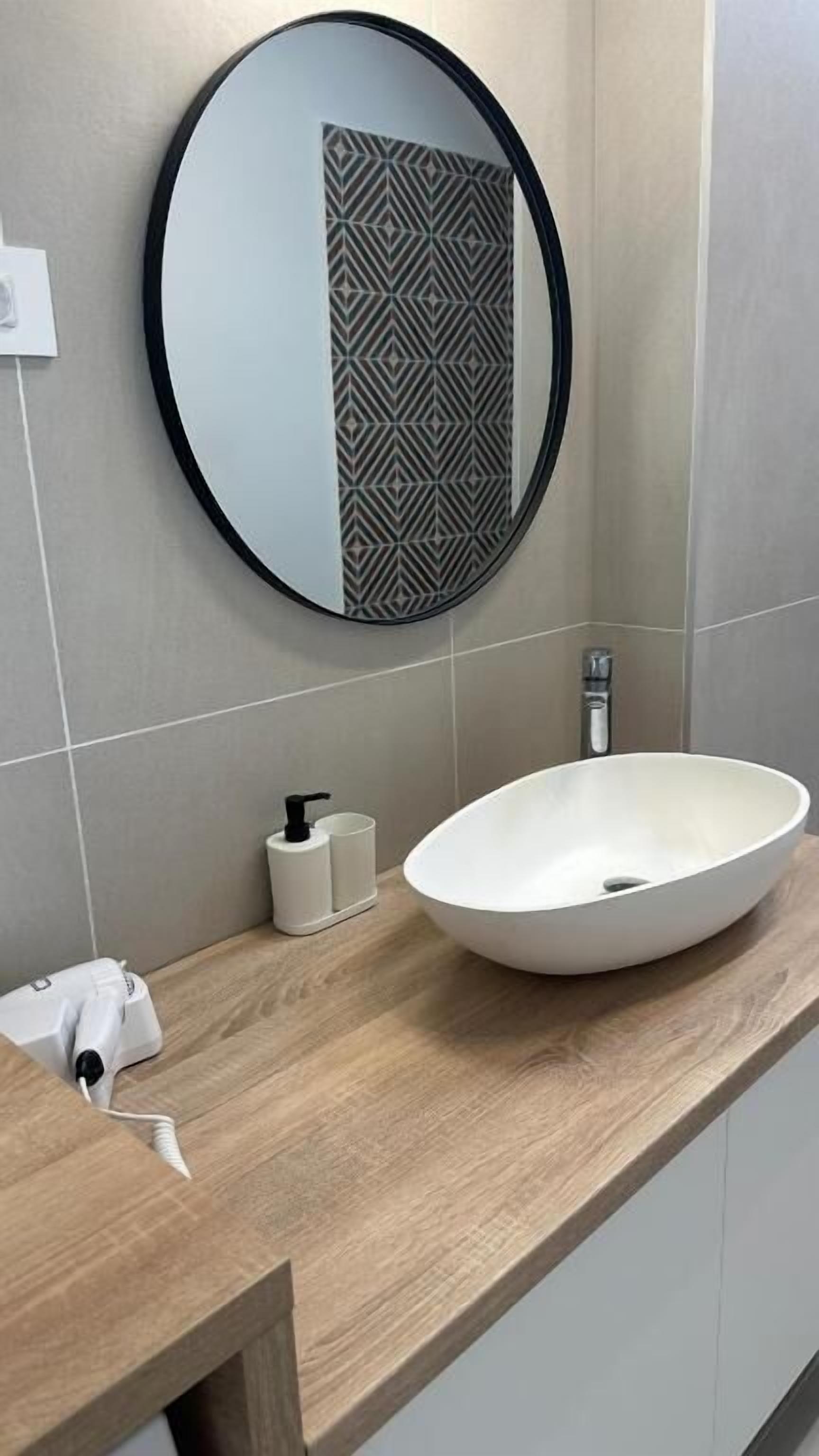 A bathroom with a round mirror, a white sink, and a towel rack.