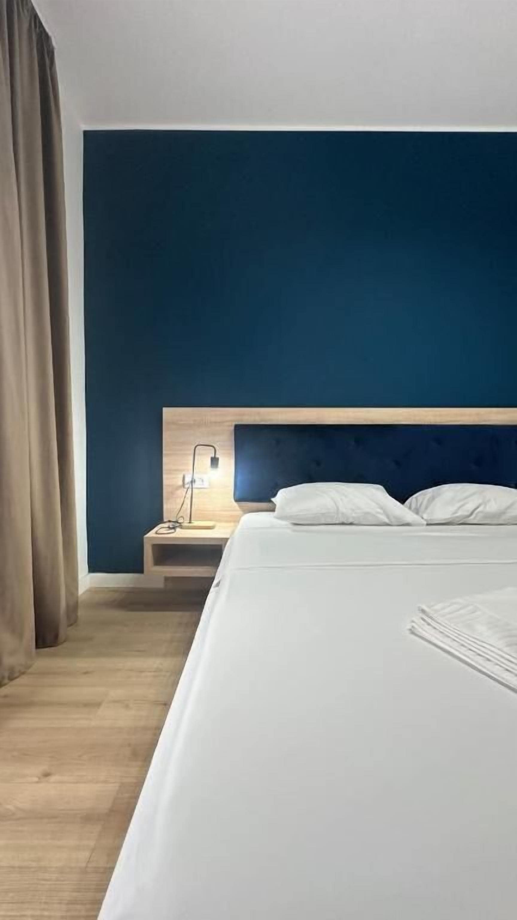 A hotel room with a large bed, a bedside table, and a nightstand.