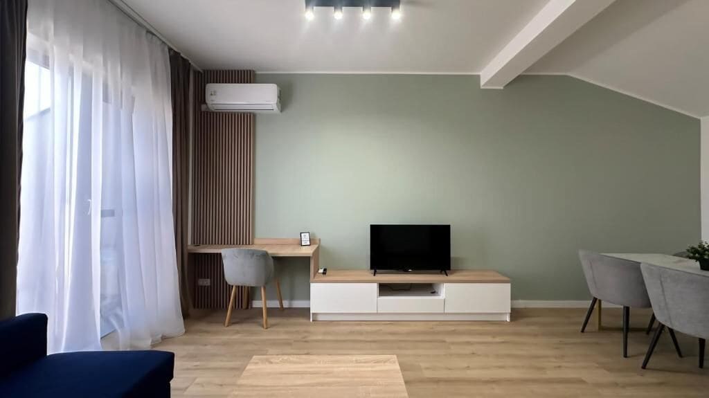 Una sala de estar moderna con un televisor de pantalla plana, un escritorio y un comedor.