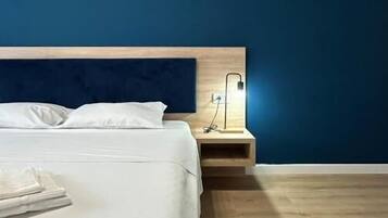 Ett sovrum med en säng, ett sängbord och ett litet bord vid sängen med en lampa.