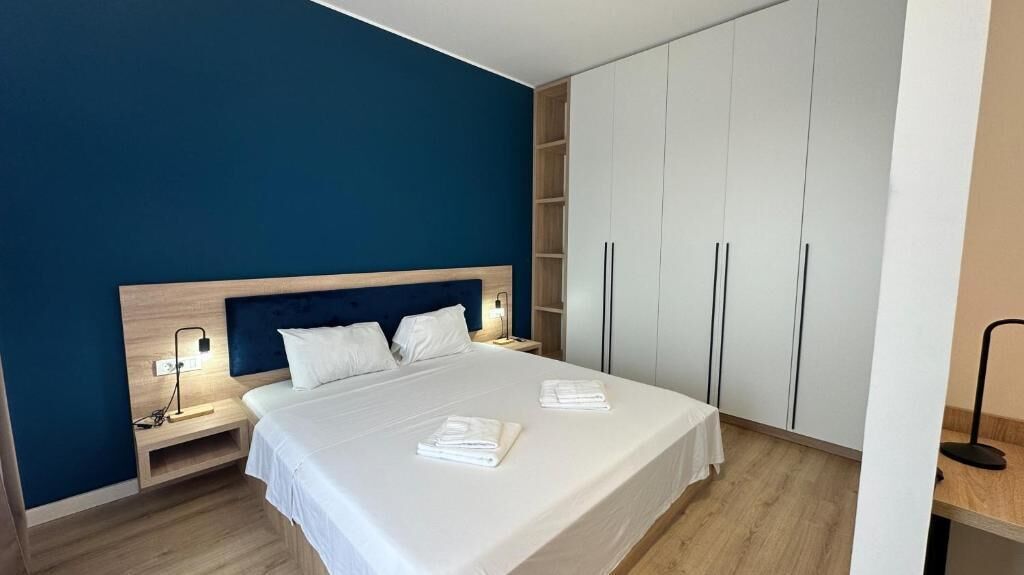 A bedroom with a bed, bedside tables, a wardrobe, and a nightstand.
