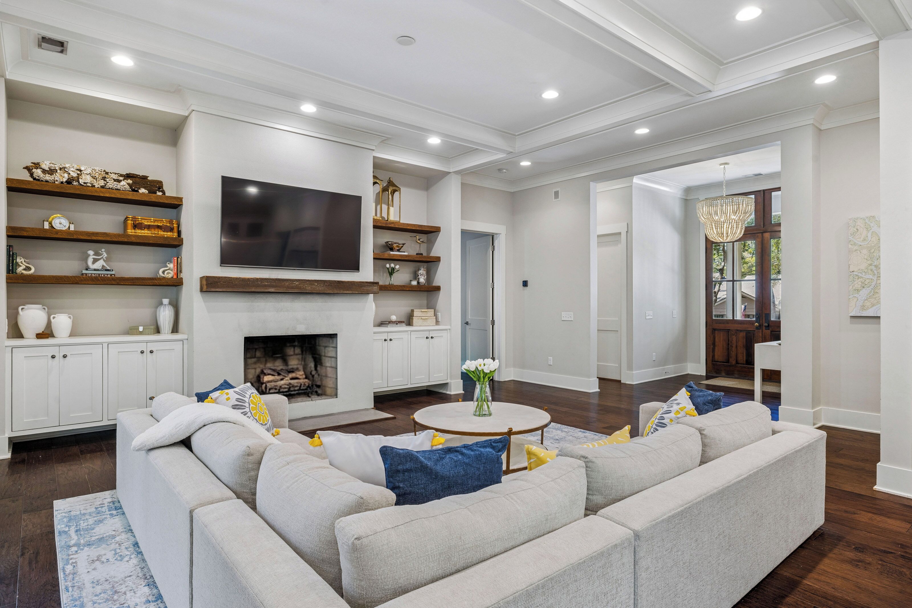 A modern living room with a sectional sofa, a fireplace, and a flat-screen TV mounted above it.