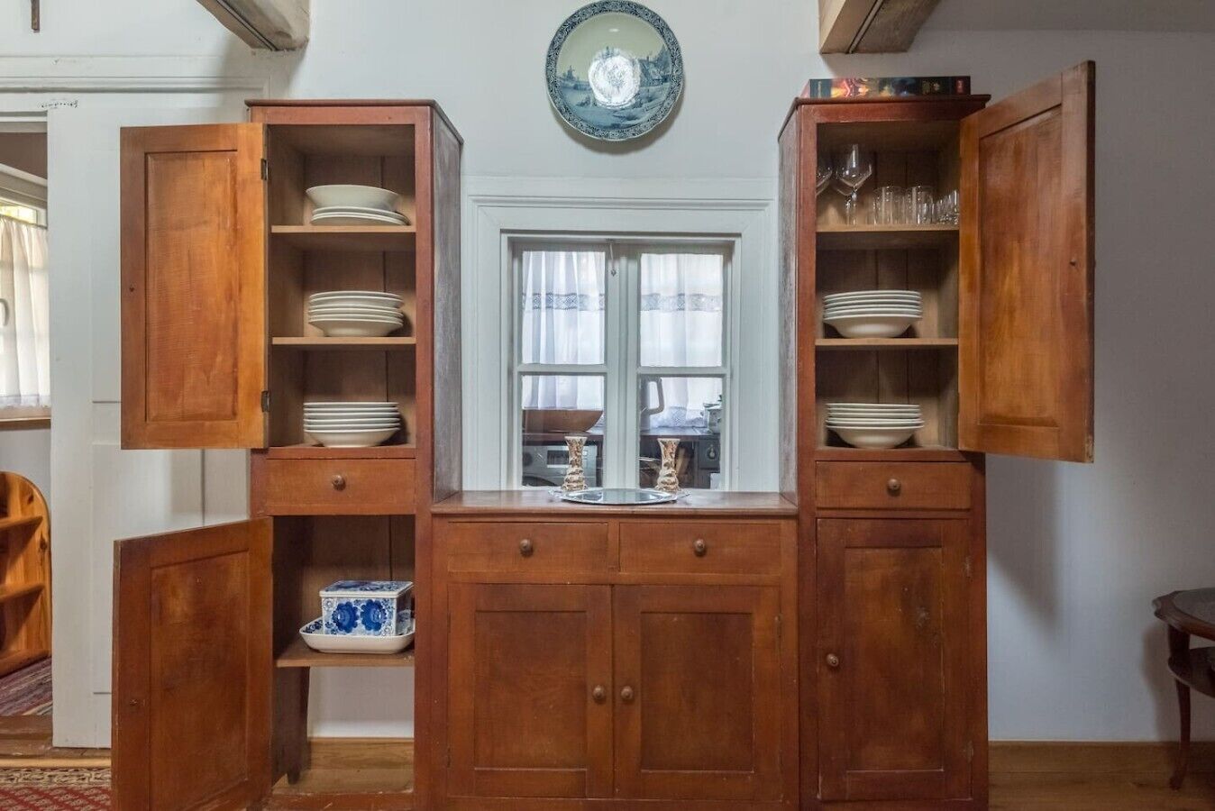 A wooden cabinet with open doors displaying plates and bowls.