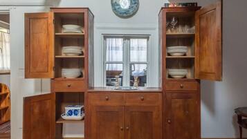 A wooden cabinet with open doors displaying plates and bowls.