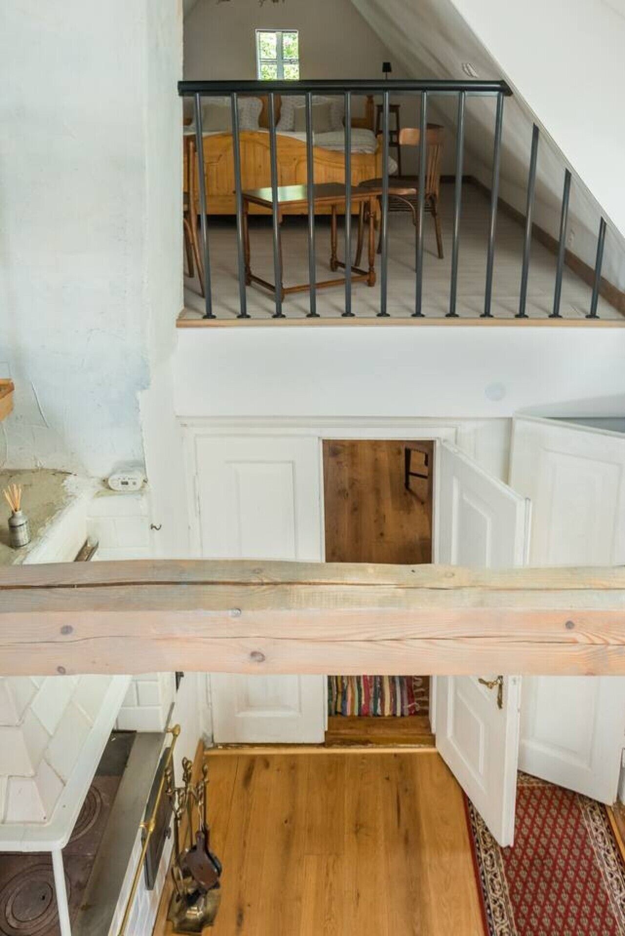 A multi-level interior with a staircase, wooden flooring, and white walls.