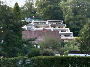A multi-story building with a flat roof, surrounded by dense greenery and trees. - Terrace Apartment in the Harz with Mountain View, Private Terrace, and Wi-Fi (Bad Harzburg)