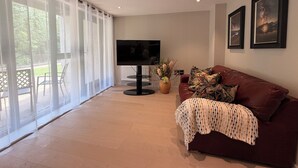 A living room with a TV, a couch, a plant, and a view of the outdoors. - The Ironworks (Ulverston)