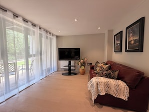 A living room with a TV, a couch, a plant, and a view of the outdoors. - The Ironworks (Ulverston)