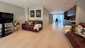 A modern living room with a leather sofa, a flat-screen TV, and a dining area with a table and chairs. - The Ironworks (Ulverston)