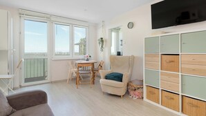 A room with a dining table, chairs, a sofa, a TV, and a cabinet. - Sunny Studio with a Balcony | Gdańsk | Close to Nature (Gdańsk)