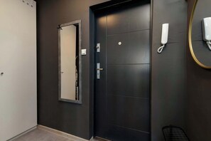 Ein Zimmer mit dunkler Wand, einer weißen Tür, einem Spiegel und einem Telefon.