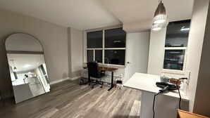 Una habitación con escritorio, silla, ventanas amplias y un espejo.